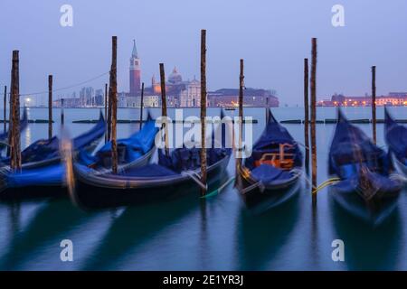 Gondola veneziana all'alba, gondole ormeggiate a Venezia con il Monastero di San Giorgio sullo sfondo, Italia Foto Stock