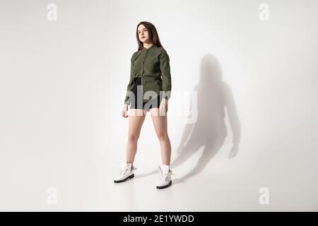 Elegante giovane donna con outfit casual su sfondo grigio Foto Stock