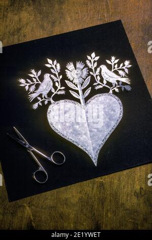 Scherenschnitte che significa tagli a forbice in tedesco è la tecnica di taglio di carta continuo disegni. Foto Stock