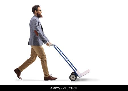 Foto di profilo di lunghezza completa di un uomo bearded che cammina e. spingere un carrello manuale vuoto isolato su sfondo bianco Foto Stock