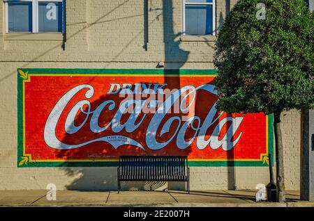 Un murale di Coca-Cola adorna il muro di un'azienda mentre il sole tramonta nel centro di Corinth, Mississippi. Corinth Coca-Cola Bottleworks fu fondata nel 1907. Foto Stock