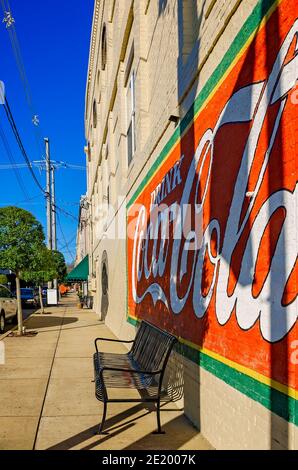 Un murale di Coca-Cola adorna il muro di un'azienda mentre il sole tramonta nel centro di Corinth, Mississippi. Corinth Coca-Cola Bottleworks fu fondata nel 1907. Foto Stock