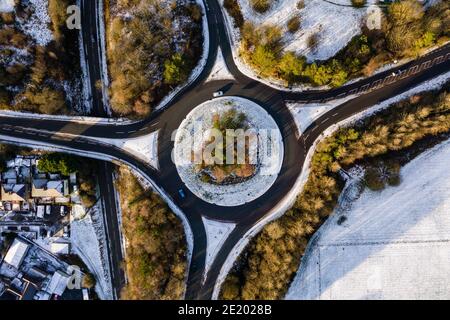 Vista aerea di una rotatoria del traffico e degli incroci stradali una giornata innevata in inverno Foto Stock
