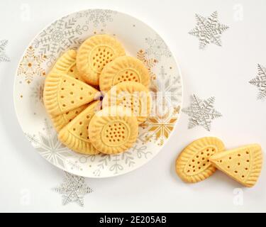 Tutti i biscotti shortbread al burro su piastra bianca con fiocchi di neve decorativi in formato piatto. Foto Stock