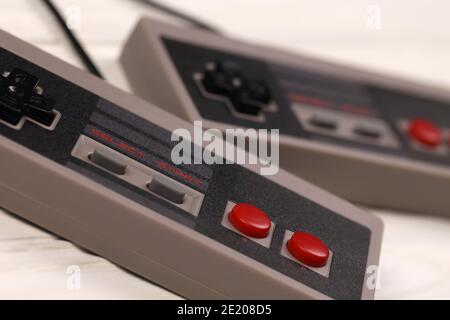 KHARKOV, UCRAINA - 27 DICEMBRE 2020: Due vecchi gamepad per console di videogiochi a 8 bit Nintendo sistema di intrattenimento e Nes mini su tavolo di legno bianco. Foto Stock