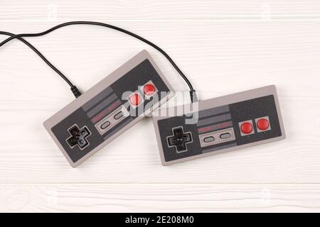 KHARKOV, UCRAINA - 27 DICEMBRE 2020: Due vecchi gamepad per console di videogiochi a 8 bit Nintendo sistema di intrattenimento e Nes mini su tavolo di legno bianco. Foto Stock