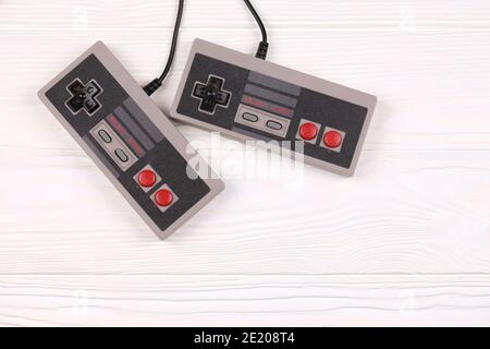 KHARKOV, UCRAINA - 27 DICEMBRE 2020: Due vecchi gamepad per console di videogiochi a 8 bit Nintendo sistema di intrattenimento e Nes mini su tavolo di legno bianco. Foto Stock