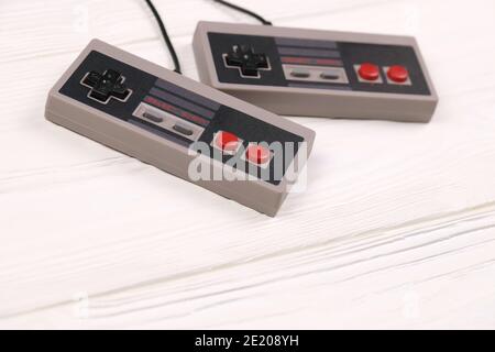 KHARKOV, UCRAINA - 27 DICEMBRE 2020: Due vecchi gamepad per console di videogiochi a 8 bit Nintendo sistema di intrattenimento e Nes mini su tavolo di legno bianco. Foto Stock