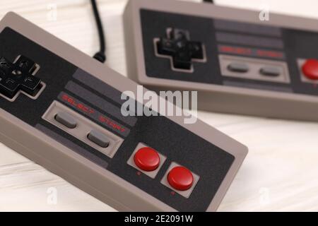 KHARKOV, UCRAINA - 27 DICEMBRE 2020: Due vecchi gamepad per console di videogiochi a 8 bit Nintendo sistema di intrattenimento e Nes mini su tavolo di legno bianco. Foto Stock