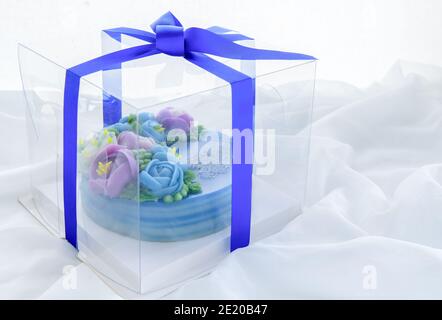 Torta minimale fatta da torta dolce dello strato del pandan e fiori graziosi della wite decorati in scatola di plastica su panno bianco. Dessert tailandese Foto Stock
