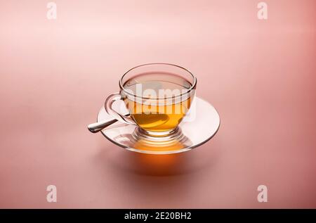 Una tazza di tè caldo appena preparato in vetro trasparente isolato su sfondo rosa. Foto Stock