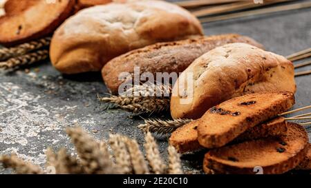 Primo piano di pane tradizionale italiano e dolci su sfondo grigio in cemento. Cantucci, ciabatta. Cucina mediterranea nazionale. Messa a fuoco selettiva Foto Stock
