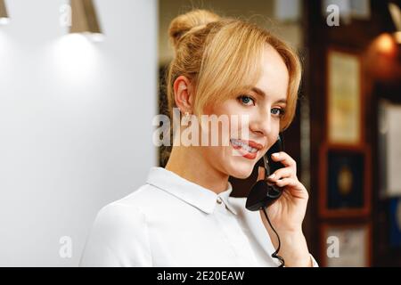 La donna che parla al telefono è un'accogliente addetta alla reception dell'hotel Foto Stock