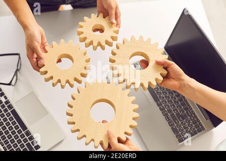 Primo piano di mani di giovani imprenditori startup collegare gli attrezzi di legno l'uno all'altro sulla scrivania in ufficio. Foto Stock