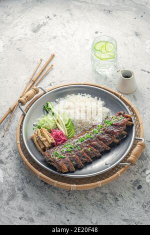 Costolette speziate di stile asiatico con riso e verdure. Foto Stock