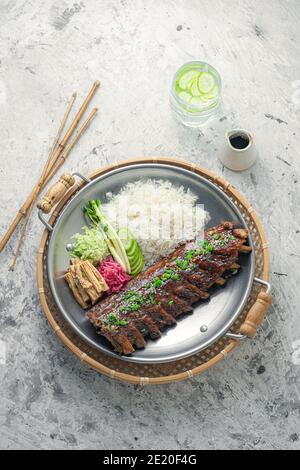 Costolette speziate di stile asiatico con riso e verdure. Foto Stock