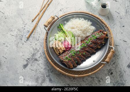 Costolette di maiale in stile asiatico con riso e verdure. Foto Stock