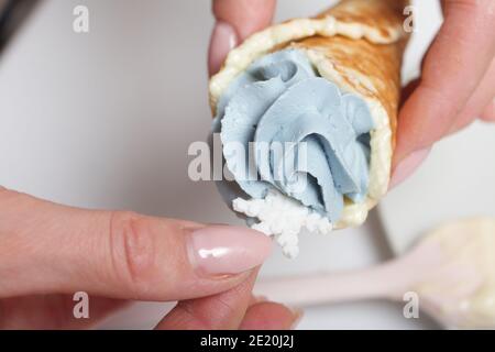 Una donna tiene in mano un cono di cialda con formaggio cremoso. Decorata con un fiocco di neve in marshmallow. Primo piano. Foto Stock