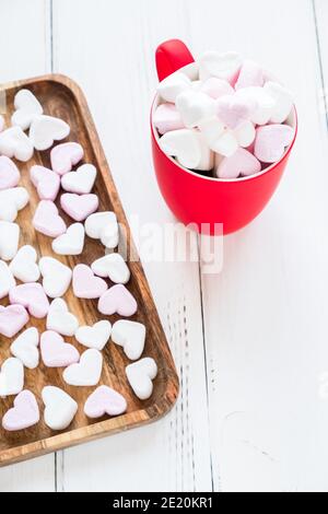 Tazza rossa di cacao caldo con marshmallows a forma di cuore sfondo bianco di legno Foto Stock