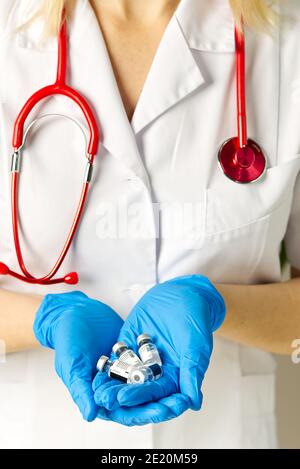 Il medico tiene in mano piccole fiale di vaccino Covid-19 Foto Stock