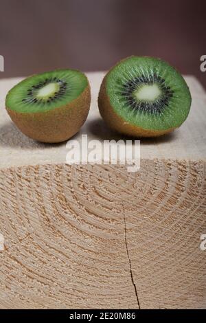 Frutta di kiwi tagliata a metà. La carne verde succosa è visibile. Si trova su un blocco di legno. Foto Stock