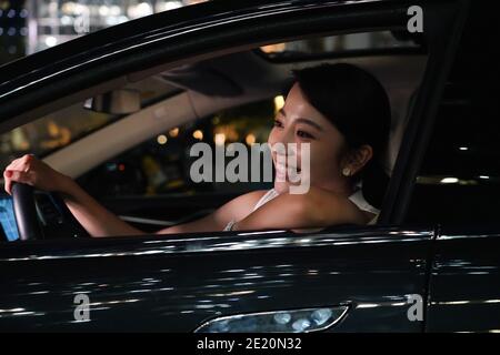 Felice giovane donna che guida di notte Foto Stock