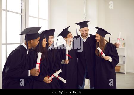 Gruppo di felici studenti universitari internazionali con diplomi che celebrano la laurea Foto Stock
