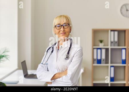 Felice medico femminile, terapeuta, medico generico guardando la macchina fotografica in piedi in ospedale Foto Stock