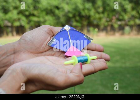 Femmina, donna, ragazza che vola un kite giocattolo in miniatura con la bobina giocattolo in miniatura manjha nel parco. In occasione di kite festa di volo di uttarayan, makars Foto Stock