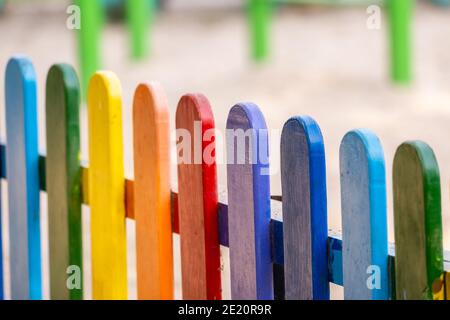 Parte di legno, arcobaleno colorato recinto dipinto in una soleggiata giornata estiva calda in un parco cittadino. Sfondo astratto multicolore. Foto Stock