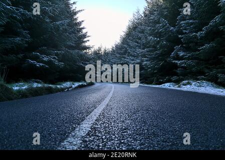 Bella vista bassa terra della strada asfaltata nella foresta invernale a Dublin Panoramic View Point, Killakee, Co. Dublino, Irlanda. Alberi di abete surgelati Foto Stock