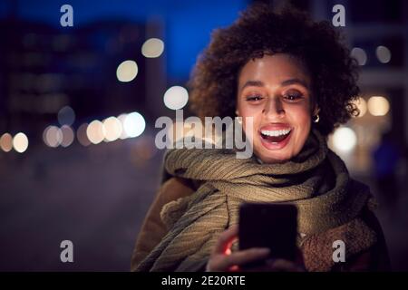 Donna su City Street a notte ordinare Taxi con il cellulare Applicazione Telefono Foto Stock