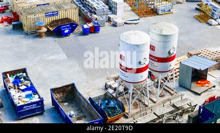 Cantiere di costruzione per costruttori con due silos di Malta Euromix, salti e container di spedizione. Per i lavoratori si può vedere un rifugio per capannone di un fumatore. Londra. Foto Stock