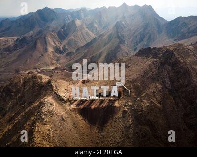 Segno di benvenuto della città di Hatta scritto con lettere grandi poste dentro Montagne Hajar nell'enclave Hatta di Dubai negli Stati Uniti Vista aerea degli Emirati Arabi Foto Stock