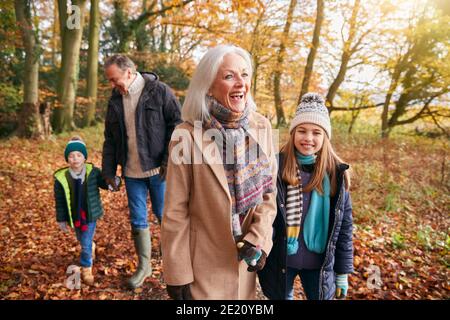 Nonni con nipoti che si godono a piedi lungo Autunno Woodland Path insieme Foto Stock