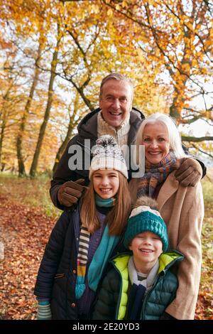 Ritratto di nonni con nipoti che si godono la passeggiata lungo Autunno Woodland Percorso insieme Foto Stock