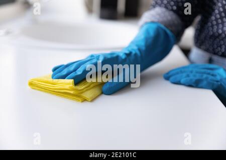 Primo piano di donna in guanti pulire i banchi da cucina Foto Stock
