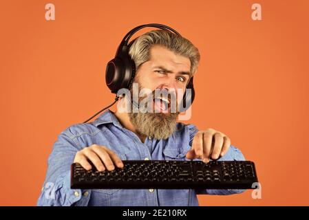 Prestazioni superiori. Giochi online. Tempo libero moderno. Eseguire qualsiasi gioco moderno. Impostazioni grafiche inviate al limite. Gioca ai giochi per computer. Cuffie e tastiera per videogamer hipster bearded uomo. Dipendenza dal gioco. Foto Stock