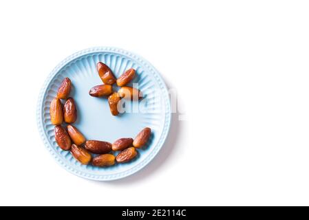 Mezzaluna islamica. Ramadan kareem con frutta datteri disposti a forma di luna crescente su piatto blu isolato su sfondo bianco, vista dall'alto, spazio copia Foto Stock