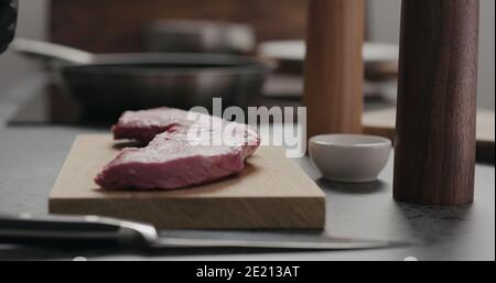 uomo mettere carne di manzo cruda su tavola di quercia, foto ampia Foto Stock