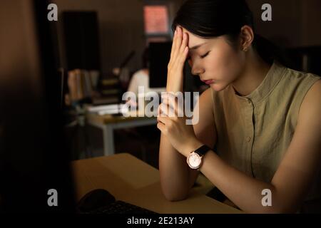 La giovane signora in ufficio per lavorare straordinario Foto Stock