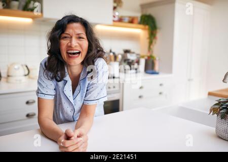 Ritratto di sorridente donna ispanica matura che indossa Pajamas trascorrere la mattina A casa in cucina Foto Stock