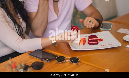 Giovane coppia godendo del tempo insieme e mangiando il velluto rosso delizioso torta Foto Stock