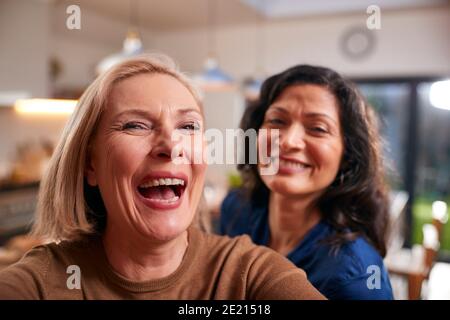 Due amici femminili mature che posano per Selfie su cellulare A casa Foto Stock