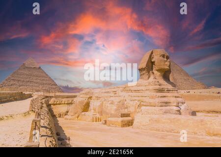 Vista della Grande Sfinge e delle Piramidi di Giza contro un colorato tramonto a Giza, Egitto Foto Stock