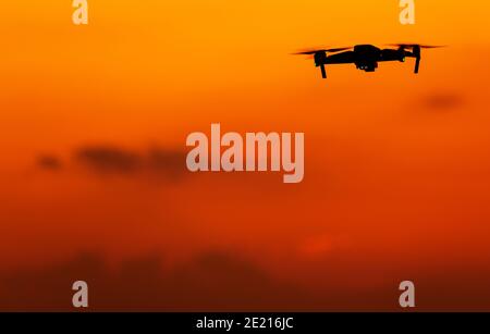 Tecnologie aeree moderne. Drone di un veicolo aereo senza equipaggio sul cielo rossastro Sunset. Ampio spazio per le copie. Foto Stock