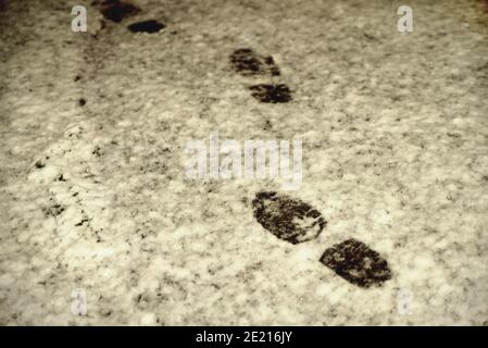 impronte nella neve di notte alla luce di una lanterna, stampe di scarpe da uomo, primo piano Foto Stock