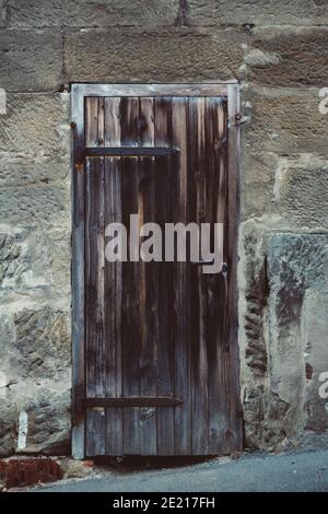 Colpo verticale di una vecchia porta di legno tradizionale con manico in metallo arrugginito sulla strada Foto Stock