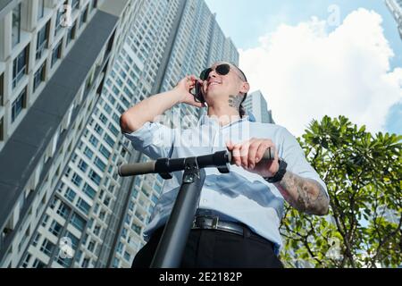 Uomo che chiama a guidare su uno scooter elettrico Foto Stock