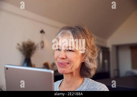 Primo piano di Smiling Mature Woman at Home con Digital Tablet Foto Stock